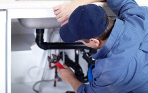 plumber repairing drain under sink